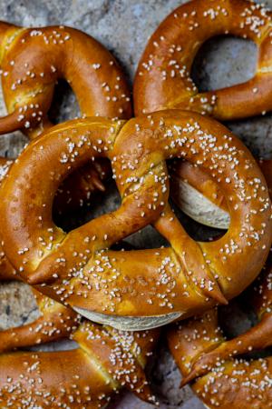 An overhead view of 5 soft pretzels on a worn metal surface.