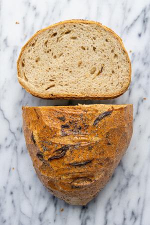 An overhead shot of an Onion Rye loaf cut in half with half laying on its end to expose the crumb.
