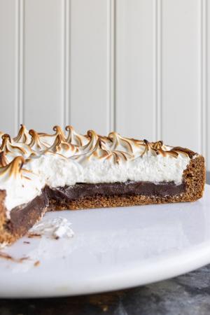 a s'mores tart on a circular platter with slices removed from it
